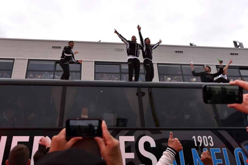 Feestvierende Heracles spelers op bus